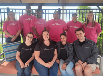 A group of people wearing pink shirts that say "First Pacific" are posing for a photo.